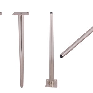 May include: Four silver metal table legs with a square base. Two legs are standing upright, and one leg is angled to show the underside of the base. The fourth leg is standing upright with a black rubber tip on the bottom.