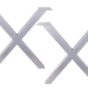 May include: Two silver metal table legs in an X shape. The legs are made of thick metal and have a smooth, polished finish.