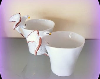 2 coffee or tea cups with a raptor eagle hanging on the edge as a handle, all in Limoges porcelain