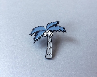 May include: A blue enamel pin of a palm tree with three white skulls for coconuts.