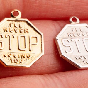 May include: Two octagonal stop sign charms, one gold and one silver, with the text "I'll Never Stop Loving You" on each.