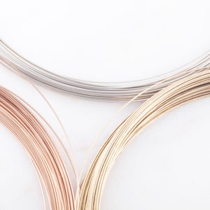 May include: Three spools of wire in different colors: silver, gold, and rose gold. The wire is wound tightly around each spool.