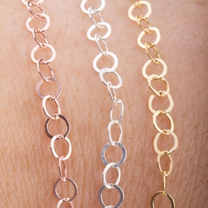 May include: Three delicate chain necklaces in rose gold, silver, and gold. The chains are made of small, interconnected circles.