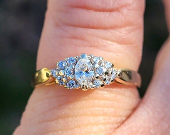 Op de afbeelding: Een gouden ring met een grote ovale diamant omringd door kleinere diamanten.