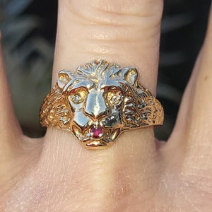 May include: A gold lion head ring with a red ruby stone in the center and two small diamonds for eyes.