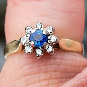 May include: A gold ring with a blue sapphire surrounded by a cluster of small diamonds.