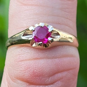 Peut inclure: Une bague en or avec une pierre précieuse rubis rouge vif sertie dans une simple bélière ronde.