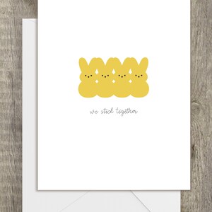 May include: A greeting card with a row of four yellow cartoon bunnies with the text "we stick together" below.