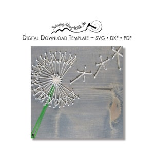 May include: A string art design of a dandelion with seeds blowing in the wind. The dandelion is made with white string and the seeds are made with white string. The background is a gray wooden surface.