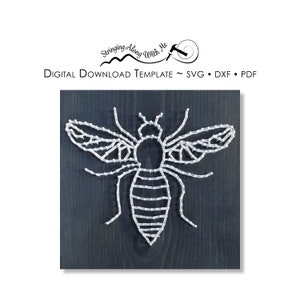 May include: A white string art bee design on a dark grey wooden background. The bee is outlined with white string and has a detailed design.