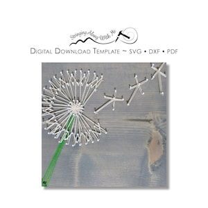 May include: A string art design of a dandelion with seeds blowing in the wind. The dandelion is made with white string and the seeds are made with white string. The background is a grey wooden surface.