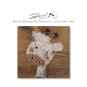 Könnte beinhalten: Ein String-Art-Design eines Giraffenkopfes auf einem Holzgrund. Die Giraffe ist aus weißem und braunem Garn gefertigt.