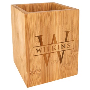 May include: A natural bamboo utensil holder with a personalized engraved design. The holder features the letter "W" with the name "WILKINS" engraved below it.