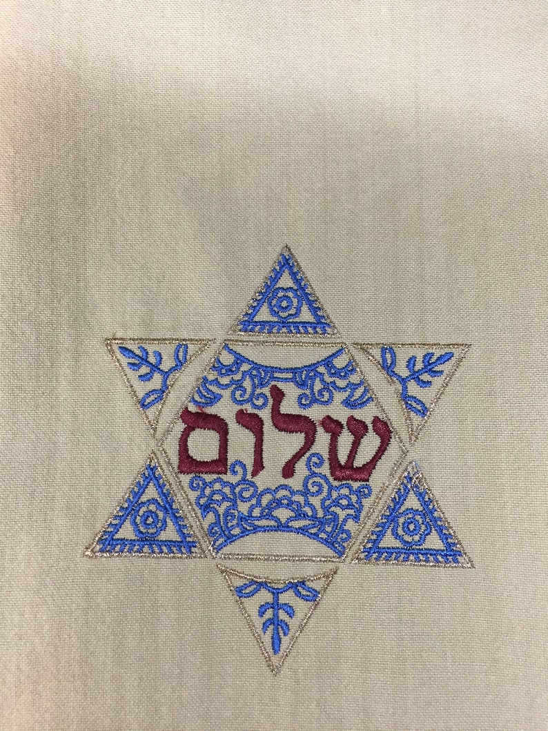 May include: A beige fabric with a blue and gold embroidered Star of David. The Hebrew word "Shalom" is embroidered in red inside the star.