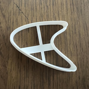 以下が含まれることがあります： 内側にクロスハッチデザインが施されたブーメラン型の白いプラスチック製のクッキーカッターです。