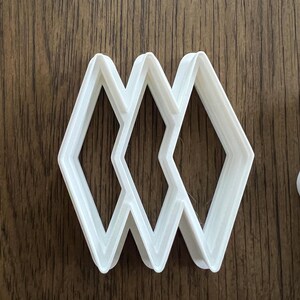 以下が含まれることがあります： 3つの重なり合ったダイヤモンドの形をした白いプラスチック製のクッキーカッター