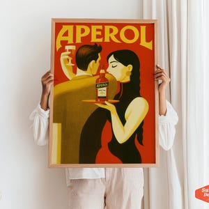 May include: A vintage-style poster advertising Aperol, a popular Italian liqueur. The poster features a couple toasting with glasses of Aperol and a bottle of the liqueur. The background is a vibrant red with yellow lettering.