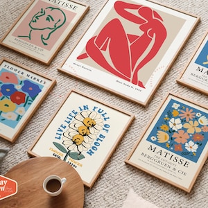 May include: A set of six framed art prints with a variety of colorful designs. The prints feature floral patterns, abstract figures, and text. The frames are all made of wood and have a natural finish.