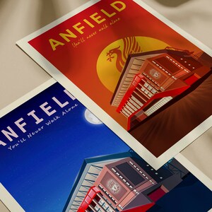 May include: Two art prints featuring Anfield stadium. One print has a red and orange background with the text "ANFIELD" and "You'll never walk alone". The other print has a blue background with the same text. Both prints have a white border.