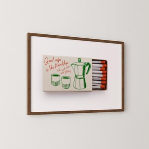 May include: A framed print of a matchbox with a green illustration of a coffee pot, two cups, and the text "Good coffee is like friendship, rich and warm and strong".