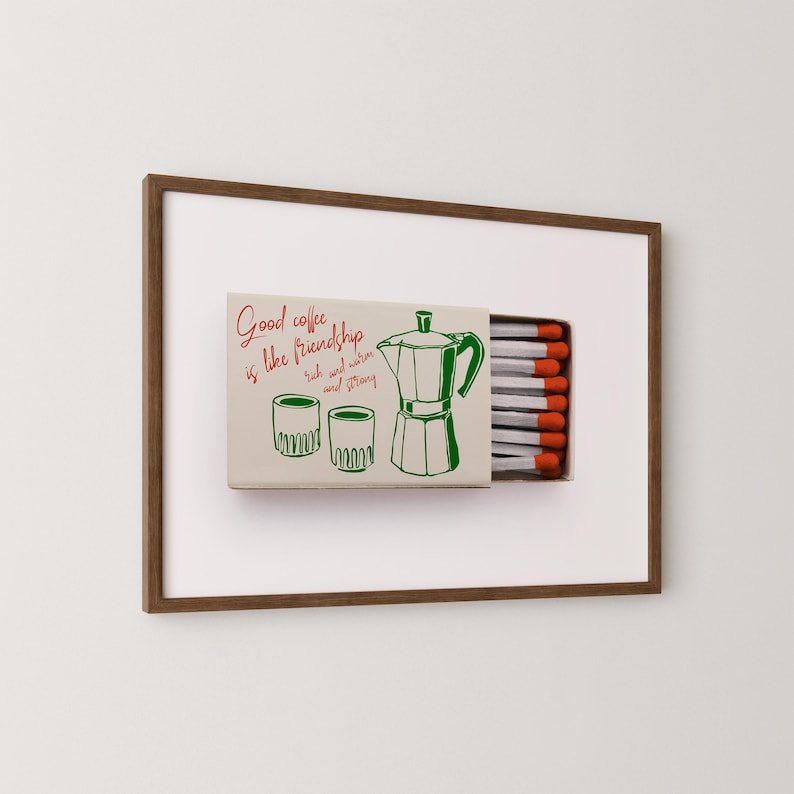 May include: A framed print of a matchbox with a green illustration of a coffee pot, two cups, and the text "Good coffee is like friendship, rich and warm and strong".