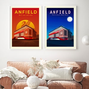 May include: Two framed art prints featuring Anfield stadium. One depicts a sunset with a Liver Bird, the other a night scene with a full moon. Both prints have the word "ANFIELD" and the phrase "You'll Never Walk Alone".