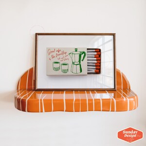 May include: A framed print with a white background and a green and red illustration of a coffee pot and two cups. The text reads "Good coffee is like friendship, rich and warm and strong".