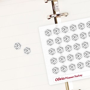May include: A sheet of planner stickers with a white background and black dice designs. The stickers are arranged in a grid pattern and have the text "Olivia Planner Factory" and "L347" printed on them.