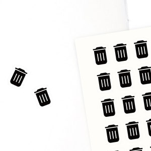 May include: A sheet of stickers featuring small black bin icons, along with two individual bin stickers. The stickers are on a white background, with a spiral-bound notebook, pink binder clips, and other stationery items.