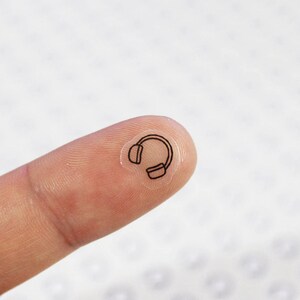 May include: A clear sticker with a black outline of headphones.