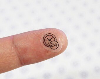 May include: Clear sticker with a black outline of a clock and the number 24 inside a circle.