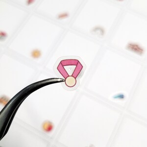 Puede incluir: Una pegatina de medalla rosa y dorada con fondo transparente.