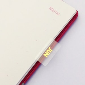 May include: A pink leather-bound notebook with a white tab labelled "Nnr" on the side. The notebook has a section labelled "Memo" at the top of the page.