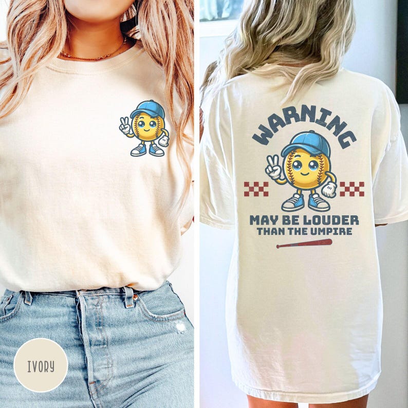 May include: A white t-shirt with a softball character graphic on the front and the text "WARNING MAY BE LOUDER THAN THE UMPIRE" on the back. The shirt is available in ivory.