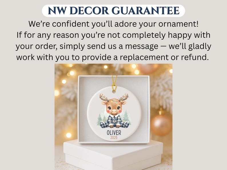 May include: A round ceramic ornament featuring a cartoon moose wearing a blue plaid outfit. The moose is sitting in front of two small green trees. The name "OLIVER" and the year "2025" are printed below the moose. The ornament is in a white box.