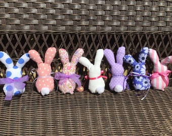 May include: Seven handmade fabric Easter bunny decorations. The bunnies are in various colors and patterns, including blue and white polka dots, pink and white polka dots, floral print, white, purple and white polka dots, blue and white floral print, and pink and white stripes.