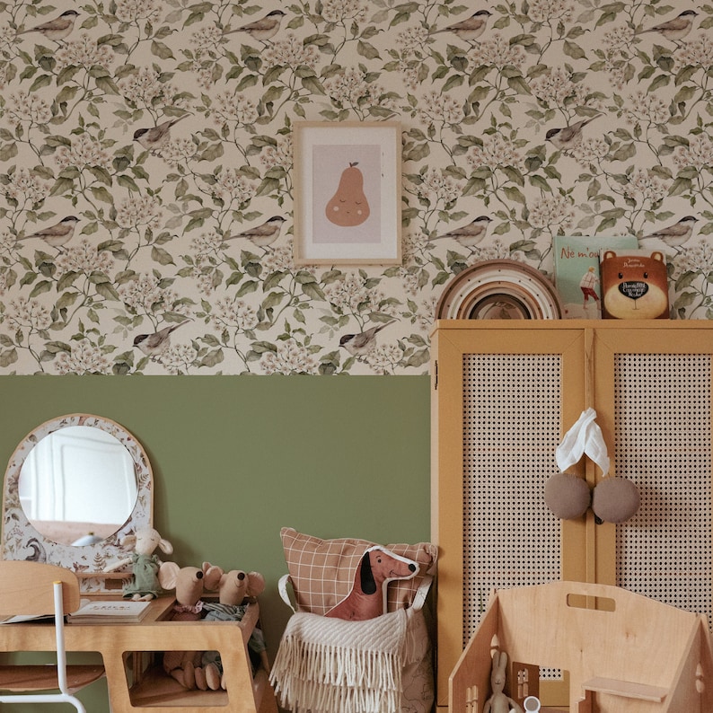 A vintage kid's room with a wooden dresser and birds beige and green wallpaper.
