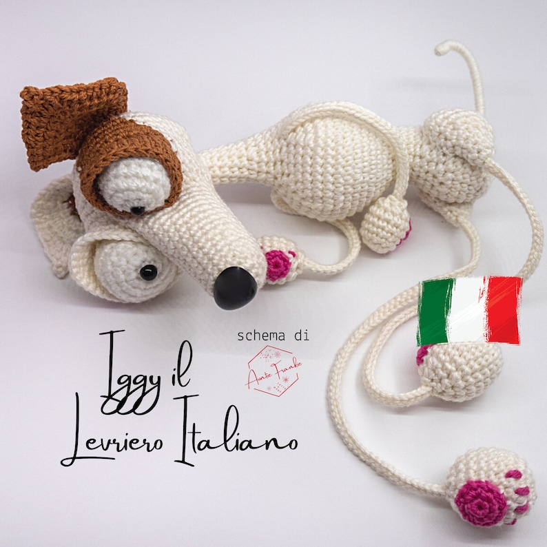 Puede incluir: Juguete de perro de galgo italiano de crochet blanco con orejas marrones y almohadillas de patas rosas. El juguete est&aacute; acostado con la cabeza girada hacia un lado. El texto "Iggy il Levriero Italiano" est&aacute; escrito debajo del juguete.