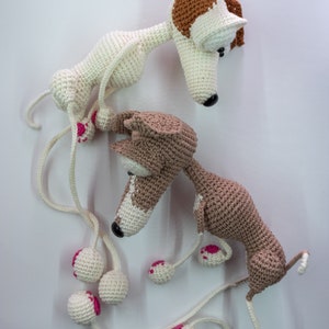 Puede incluir: Dos juguetes para perros de crochet hechos con hilo blanco y marr&oacute;n. Los perros tienen detalles de hilo rosa en sus patas y ojos. Los perros est&aacute;n conectados por una larga cuerda de hilo blanco.