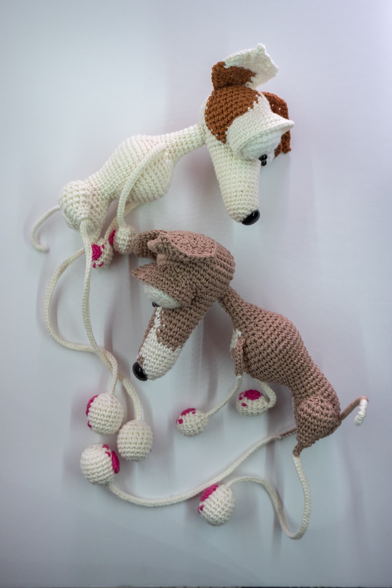 Puede incluir: Dos juguetes para perros de crochet hechos con hilo blanco y marr&oacute;n. Los perros tienen detalles de hilo rosa en sus patas y ojos. Los perros est&aacute;n conectados por una larga cuerda de hilo blanco.