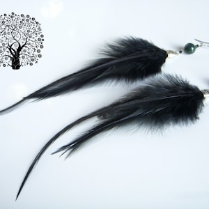 May include: A pair of long black feather earrings with green gemstone beads and silver accents.