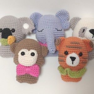 May include: Five crocheted stuffed animals: a grey koala, a light blue elephant, a white panda, a brown monkey wearing a pink bow tie, and an orange tiger wearing a green collar.