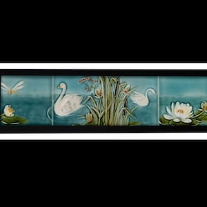 May include: A decorative tile set depicting a tranquil water scene. The artwork shows white swans, water lilies, and a dragonfly against a teal backdrop. The tiles are framed in black, creating a cohesive and artistic display, ideal for home decor.