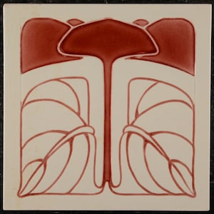 May include: Square ceramic tile with a cream background and a symmetrical design in red hues. The design features stylized floral or botanical elements, with a central stem and curved leaf-like shapes.
