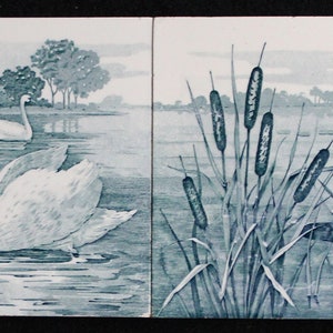 Op de afbeelding: Drie blauwe en witte keramische tegels die een serene scène van een meer met zwanen, lisdodde en waterlelies voorstellen. De tegels maken deel uit van een grotere decoratieve set.