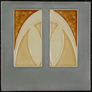 May include: A square ceramic tile with a pale blue border. The tile features two vertical rectangular designs with a cream-coloured, abstract floral pattern. The background of the design is a light tan colour.