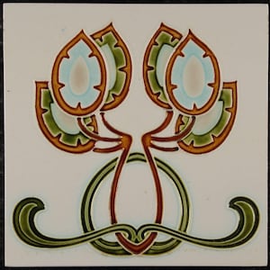 May include: Square ceramic tile with an Art Nouveau floral design. The design features two stylized flower-like shapes in shades of brown, green, and light blue, set against a white background. A green and brown decorative border is at the bottom.