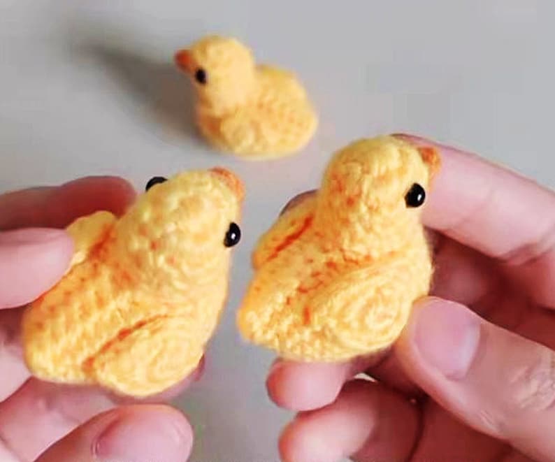 Puede incluir: Tres pollitos amarillos de crochet con ojos negros. Los pollitos son peque&ntilde;os y se sostienen en manos.