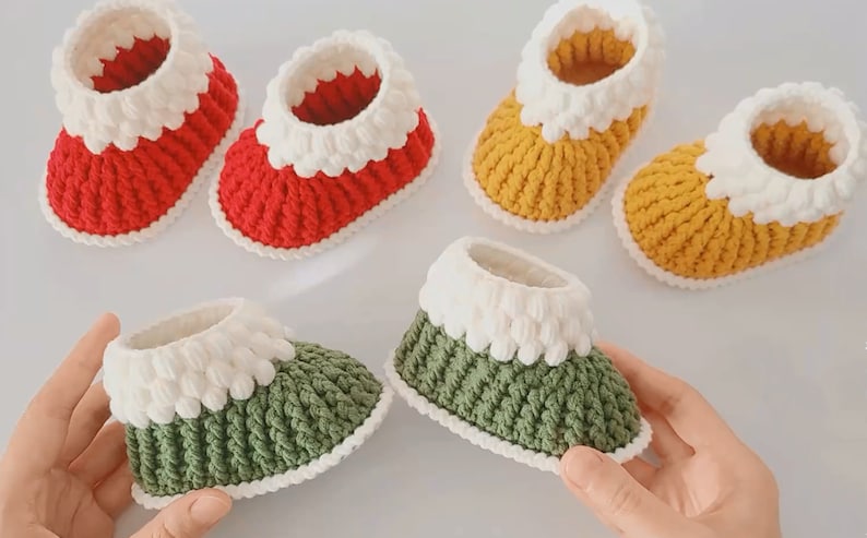Puede incluir: Cuatro pares de botines de beb&eacute; tejidos a crochet en rojo, amarillo, verde y blanco. Los botines tienen un pu&ntilde;o tejido a crochet blanco y un cuerpo de color contrastante.