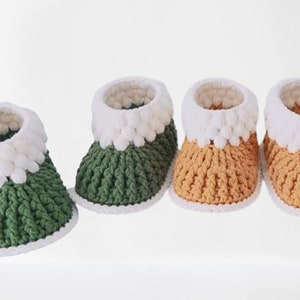 Puede incluir: Tres pares de botines de beb&eacute; tejidos a crochet en verde, naranja y blanco. Los botines tienen un pu&ntilde;o blanco tejido a crochet.